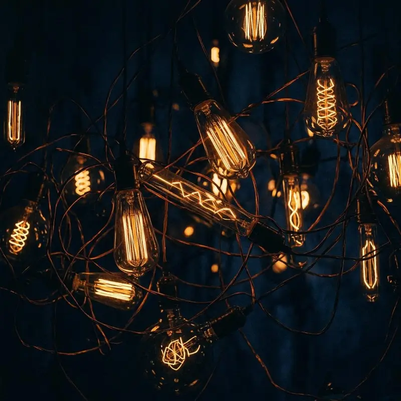 Copper wire and a glowing amber bulb filament on a dark navy background